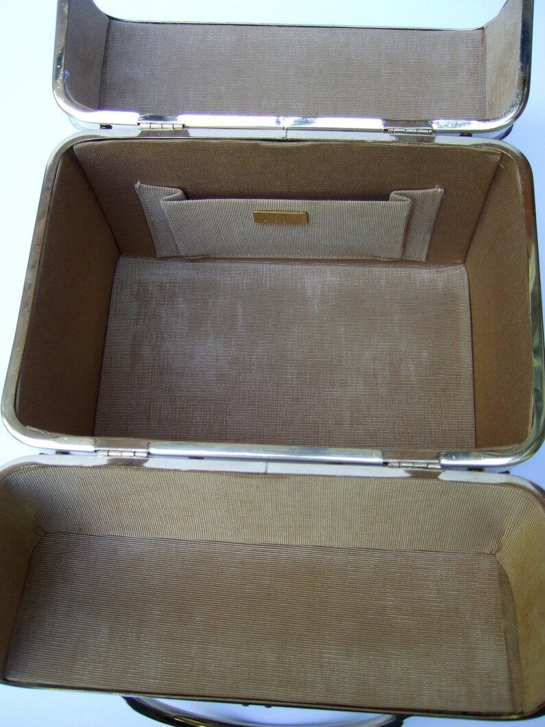 K&ouml;nnte beinhalten: Eine leere, rechteckige Box mit drei F&auml;chern, die mit braunem Stoff ausgekleidet ist, silberfarbene Verzierungen hat und ein kleines Fach im Inneren des oberen Fachs.