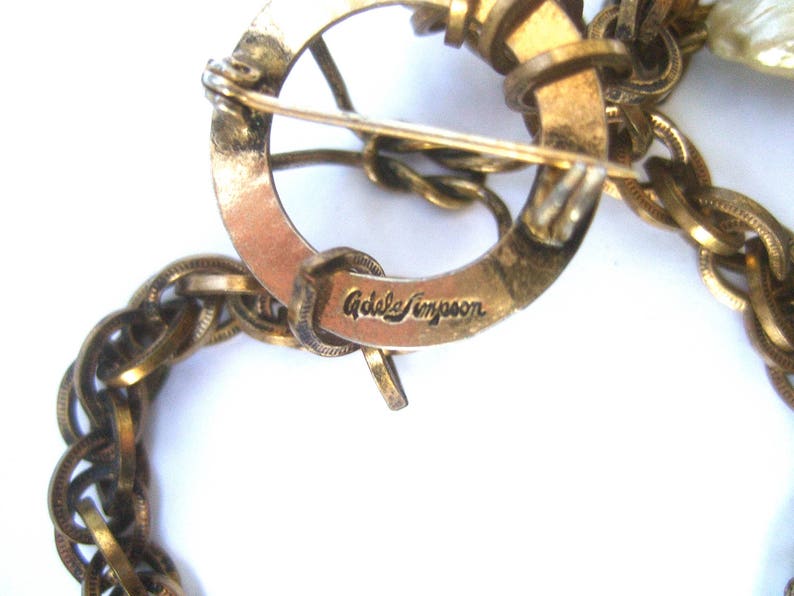 May include: A gold-toned chain necklace with a clasp that reads "Adele Simpson".