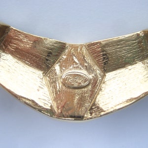 May include: Gold-toned metal necklace with a geometric design and a 'Tiffari' logo.