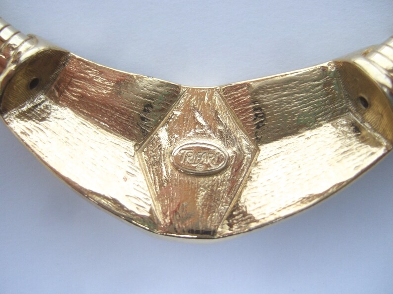 May include: Gold-toned metal necklace with a geometric design and a 'Tiffari' logo.