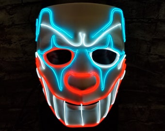 May include: A white plastic mask with a neon blue and red light design. The mask has a wide smile with teeth and a large, round nose.