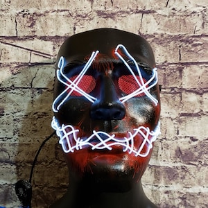 May include: A black plastic mask with white LED lights forming a pattern over the eyes and mouth. The mask has red accents around the eyes and mouth.