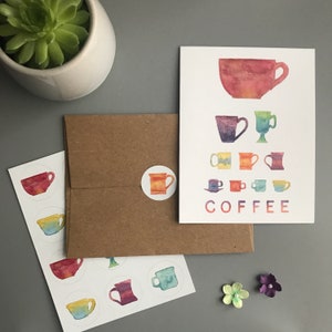 May include: A set of coffee-themed stickers with a variety of colorful mugs and the word "COFFEE" in a rainbow font. The stickers are on a white sheet of paper with a brown envelope and a small potted succulent plant in the background.