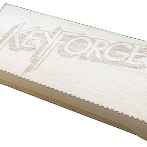 May include: A wooden box with a laser-engraved design of the word "KEYFORGE" on the top.