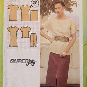 May include: Simplicity sewing pattern 9078. The pattern includes illustrations of a top, skirt, and pants. The package features a woman wearing a beige top and a burgundy skirt. The text on the package reads "Simplicity" and "SUPER Jiffy".