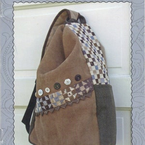 May include: A brown suede side pack sack with a patchwork design and buttons. The bag is hanging on a white door. The text "side pac sack" and "MINIATURE QUILT ART" is printed on the image. The text "galloping pony studio" is printed at the bottom of the image.