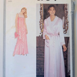 May include: Simplicity 8764 sewing pattern featuring a pink nightgown and robe. The pattern includes a size 12 Miss option. The image shows illustrations of the garments, with a woman modeling the nightgown and robe.