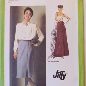 May include: Simplicity sewing pattern 9113. The pattern features a woman wearing a cream-colored blouse and gray skirt. The waist size is 30 inches. The pattern also shows a long burgundy skirt and a cream-colored top. The brand name "Jiffy" is visible.
