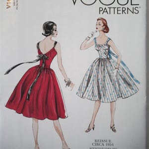 May include: Vogue Patterns sewing pattern for two dresses. The pattern is a reissue from circa 1954. One dress is red with a black sash and the other is a blue and white striped dress with a blue sash.