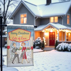 May include: A festive Christmas garden flag featuring a retro illustration of a couple. The flag displays the message "Merry Christmas with Lots of Love". The background shows a snow-covered house decorated with Christmas lights.