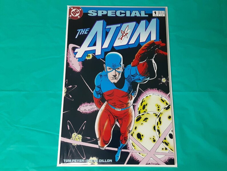 May include: A comic book cover featuring the Atom, a superhero in a red and blue costume, flying through space. The cover is titled "Special The Atom" and is issue number 1. The cover art is by Tom Peyer and Steve Dillon.