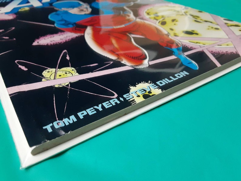 May include: A comic book cover featuring a superhero in a blue and red costume flying through space. The cover is titled "Atom" and features the artist's name "Tom Peyer, Steve Dillon".