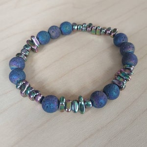 May include: A dark blue lava rock bracelet with iridescent metal beads. The bracelet is made of natural lava rock and metal beads.