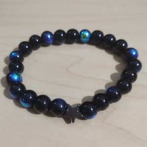 May include: A black beaded bracelet with iridescent blue beads and a black star charm.