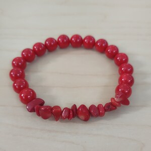 May include: A red coral beaded bracelet with a row of smaller, flat coral pieces.