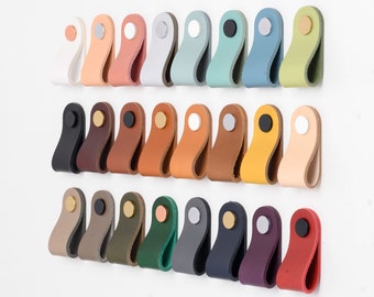 May include: Assortment of 24 leather cabinet pulls in various colors, including black, brown, white, green, blue, red, and beige. Each pull has a round metal knob.
