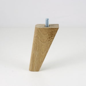 May include: A light brown wooden furniture leg with a slanted top and a metal screw in the top.