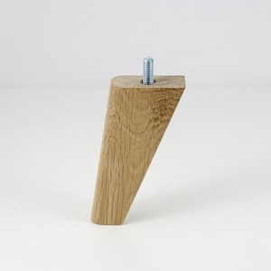 May include: A light brown wooden furniture leg with a slanted top and a metal screw. The leg is about 10 inches tall.