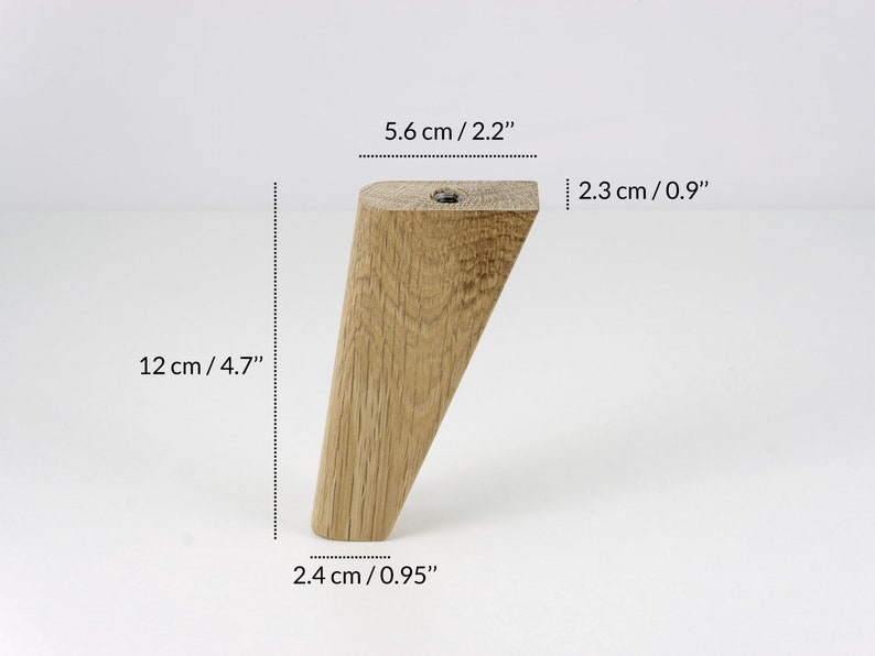 May include: A wooden furniture leg with a tapered design. It measures 12 inches in length, 2.2 inches in width, and 0.95 inches in thickness.