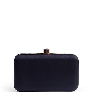 Puede incluir: Un clutch de sat&eacute;n negro con cierre de oro rosa y un adorno de cristal transparente.