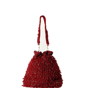 May include: A red beaded drawstring bag with a long strap. The bag is made of small, tightly woven beads.