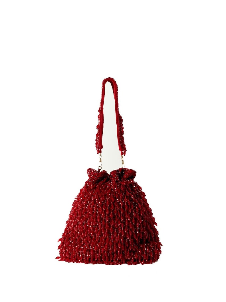 May include: A red beaded drawstring bag with a long strap. The bag is made of small, tightly woven beads.