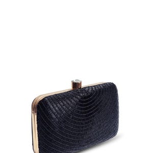 Puede incluir: Un clutch negro de cuentas con marco dorado y cierre de cristal transparente.