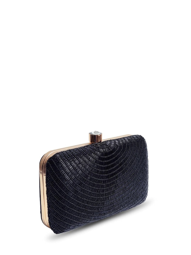 Puede incluir: Un clutch negro de cuentas con marco dorado y cierre de cristal transparente.