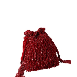 May include: A red beaded drawstring bag with a tassel. The bag is made of small, round beads that are sewn together to create a textured surface.