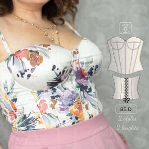 May include: A white floral print corset top with a pink skirt. The image also shows a line drawing of a corset with two different styles and lengths. The text on the image reads "85 D, 2 styles, 2 lengths".