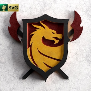 Puede incluir: Un escudo negro con un diseño de dragón dorado en su interior. Dos hachas rojas se cruzan detrás del escudo.