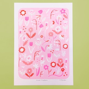 Op de afbeelding: Een roze kunstafdruk met een grillig bloemenontwerp. De print toont verschillende bloemen in roze en rode tinten, met lachende en verdrietige gezichten. De tekst "Mixed Emotions" staat onderaan.