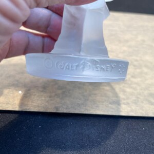 May include: A clear glass figurine with a base that reads "&copy; WALT DISNEY"