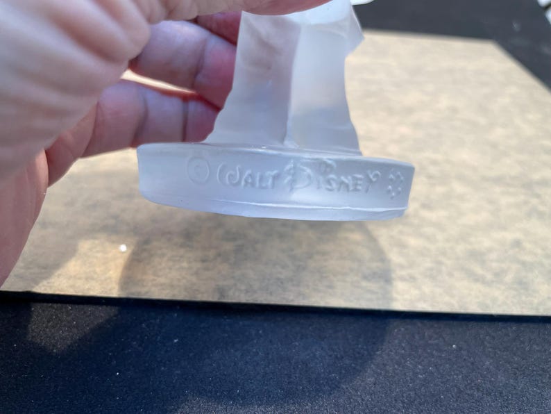May include: A clear glass figurine with a base that reads "&copy; WALT DISNEY"