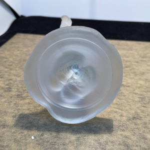 May include: The bottom of a frosted glass vase with a round base and a textured design.