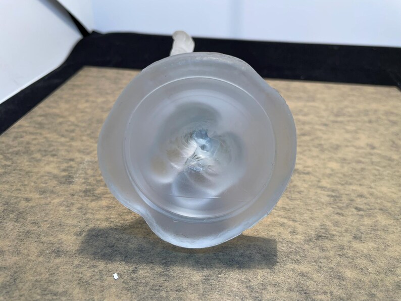 May include: The bottom of a frosted glass vase with a round base and a textured design.