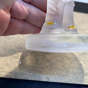 Puede incluir: Una figurita de vidrio transparente de una persona con sombrero y botas. La figurita est&aacute; de pie sobre una base de vidrio transparente con las palabras "Baccarat France" inscritas en la parte inferior.