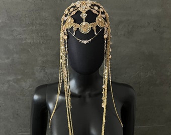 May include: A gold headpiece with dangling chains and crystals. The headpiece is made of metal and has a delicate, intricate design.