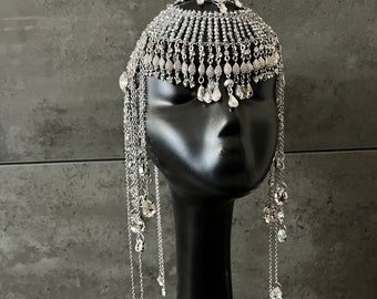 May include: A silver headpiece with dangling chains and crystal beads. The headpiece is made of metal and has a delicate, intricate design.