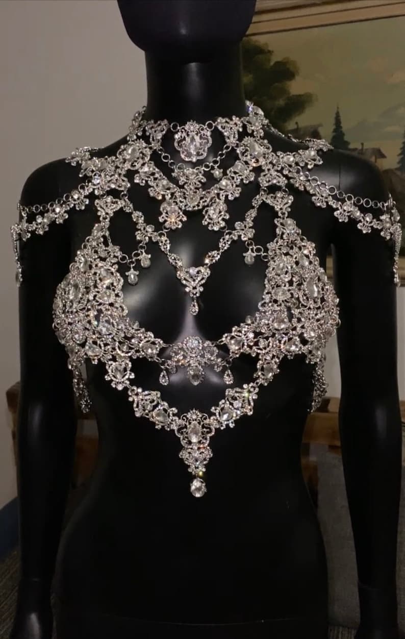 Puede incluir: Una cadena de cuerpo plateada de varios niveles, incrustada con diamantes de imitaci&oacute;n, con un delicado colgante.