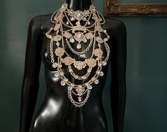 May include: A multi-layered gold and crystal necklace with a variety of pendant shapes and sizes. The necklace is displayed on a black mannequin.