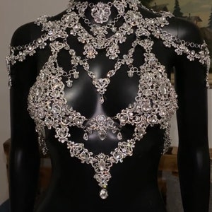 Puede incluir: Una cadena de cuerpo plateada con m&uacute;ltiples capas de cadenas delicadas y diamantes de imitaci&oacute;n. La cadena est&aacute; dise&ntilde;ada para usarse alrededor del cuello y los hombros, con un colgante que cuelga del centro.