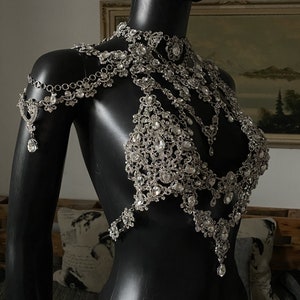 Puede incluir: Una cadena de cuerpo plateada con un dise&ntilde;o delicado que presenta muchos peque&ntilde;os diamantes de imitaci&oacute;n. La cadena est&aacute; en capas e incluye un collar, una parte superior estilo sujetador y un colgante largo.