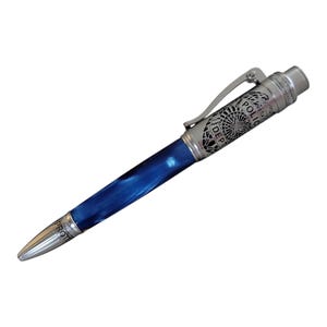 May include: A silver pen with a blue and white marbled design. The pen has a silver clip and a silver cap with an engraved police badge design. The engraving reads "Police Dept."