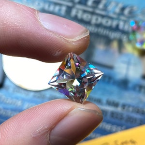 Può includere: Una gemma trasparente, sfaccettata e di forma quadrata con colori iridescenti arcobaleno.