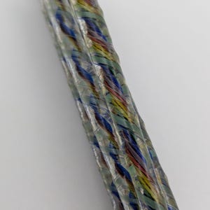 May include: Close-up of a multi-colored cable with a clear outer sheath. The cable is made up of several smaller wires, each wrapped in a different color of insulation. The colors include blue, green, red, and yellow.
