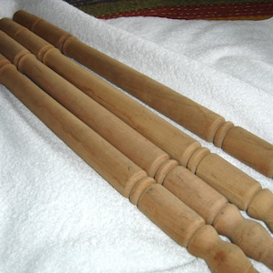 May include: Four wooden chair legs with turned details. The legs are unfinished and have a natural wood color.