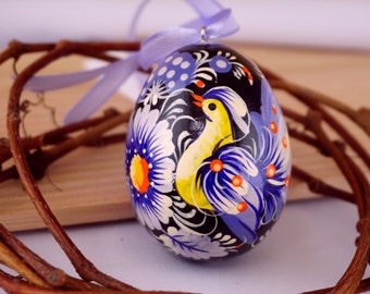 Ovo de Páscoa ucraniano pintado à mão com um pássaro azul e um padrão floral colorido, de acordo com a tradição artística da pintura de Petrykivka.