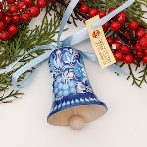Peut inclure: Une cloche en bois peinte à la main, bleue et blanche, avec un motif floral. La cloche est attachée à un ruban bleu et possède un petit battant en bois. La cloche est un ornement traditionnel de l'art populaire ukrainien.