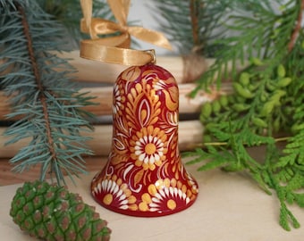 Kerstboomversiering van hout, handgeschilderde rood-gouden nostalgische kerstbel met Oekraïense Petrykivka-schildering in bloemmotief
